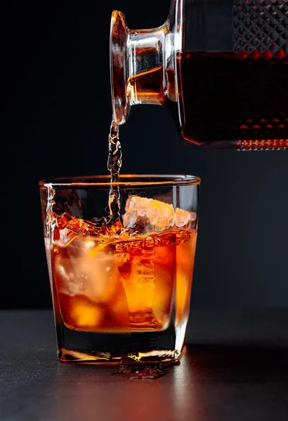 Viski buğulanmış bir bardağa doğal buzla doluyor. Alkol içeceği kristal bir sürahide bardağa dökülür..