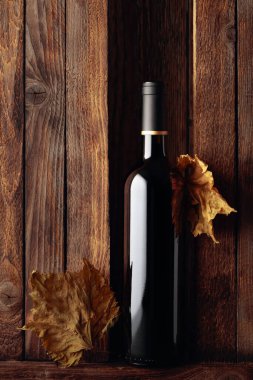 Eski ahşap arka planda bir şişe kırmızı şarap. İçeriğiniz için boş alan.