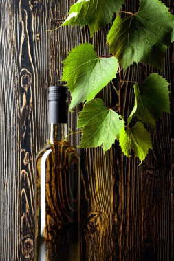 Açılmamış bir şişe beyaz şarap ve eski ahşap arka planda bir dedikodu. Boşluğu kopyala.