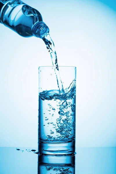 Versare Acqua Una Bottiglia Bicchiere Uno Sfondo Blu Copia Spazio — Foto Stock