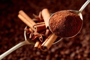 Kahve çekirdeğinin arka planında tarçın çubukları olan kaşık dolusu kahve ve anason.. 