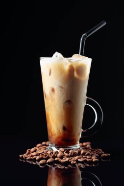 Siyah yansıtıcı arka planda buzlu kahve. İçine krema dökülüyor. İçkinin dokusunu ve ferahlatıcı bakışını gösteriyor.. 