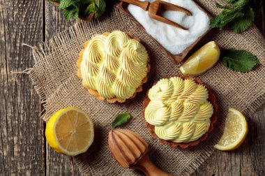 Eski ahşap bir masada limon kremalı ve naneli tart. Üst görünüm.