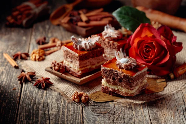 Layered cakes with spices and nuts on a old wooden table. Romantic breakfast with rose.