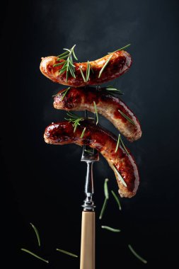 Biberiyeli ızgara sosis. Biberiye serpilmiş çatallı sıcak sosisler..