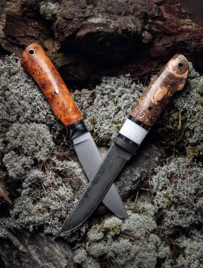 Avcı el, ormanda yosun üzerinde bıçak yaptı. Bıçağın yüzeyi - oyma, dövülme izleri. Üst görünüm.