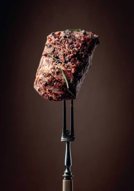 Kahverengi arka planda biberiyeli ızgara biftek. Çatallı biftek..