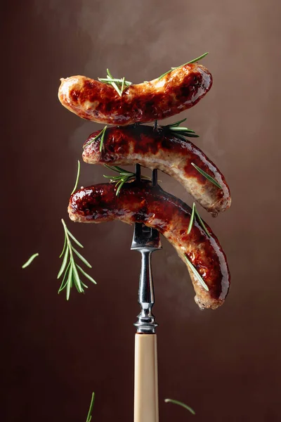 烤巴伐利亚香肠配迷迭香叉子上的香肠撒满了迷迭香 棕色背景 — 图库照片