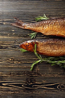Eski ahşap bir masada tütsülenmiş ringa balığı. Baltık ülkelerinde geleneksel yiyecekler. Üst görünüm.
