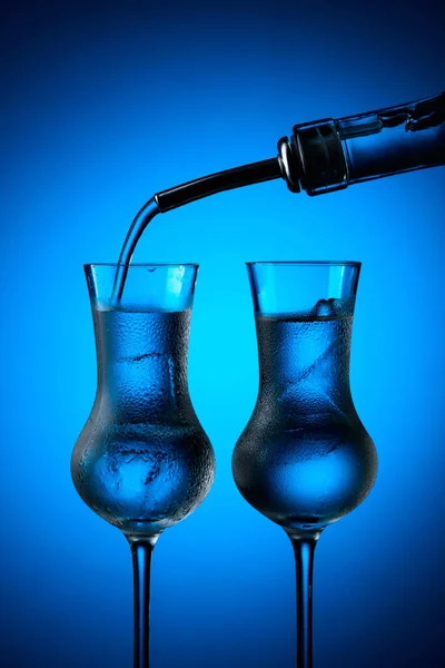 Βότκα Χύνεται Από Μπουκάλι Ποτήρια Πάγο Κατεψυγμένα Γυαλιά Σκούρο Μπλε — Φωτογραφία Αρχείου