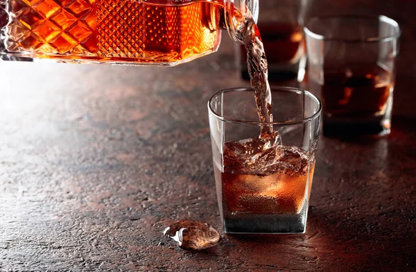 Pouring whiskey in glass with natural ice. Dammed glass  with strong alcoholic drink.