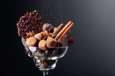 İçinde malzemeler olan çeşitli çikolatalar. Bir cam kase şeker, kahve çekirdekleri, tarçın, anason ve parçalanmış siyah çikolata. Boşluğu kopyala.