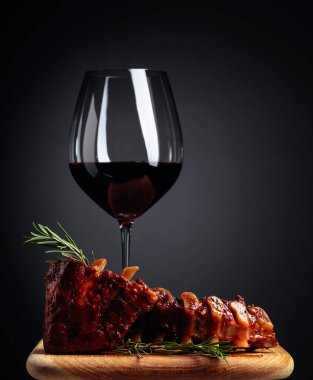 Ahşap bir tahtada ızgara domuz pirzolası, biberiye ve kırmızı şarap. Boşluğu kopyala.