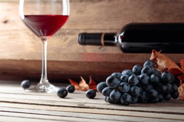 Şarap mahzenindeki eski ahşap bir masada kırmızı şarap ve bir demet üzüm. Seçici odak.