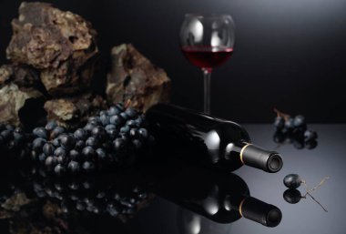 Siyah yansıtıcı arka planda mavi üzüm ve kırmızı şarap. Boşluğu kopyala.