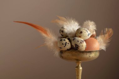 Bej arka planda pirinç kasede tüyleri olan Paskalya yumurtaları..