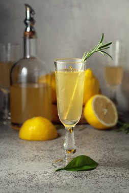Taze limonlu İtalyan likörü Limoncello ve gri taştan bir masada biberiye dalları..
