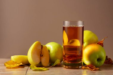 Elma suyu ve kurumuş yapraklı olgun elmalar. Kopyalama alanı olan bej arkaplan.