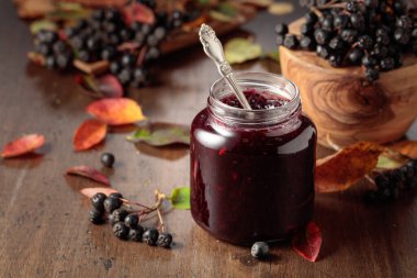 Yaban mersini reçeli ve eski ahşap bir masada yaprakları olan taze böğürtlen. Boşluğu kopyala.