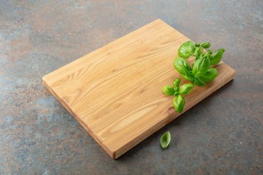 Mutfak masasında tahta ve fesleğen kesiyorum. Mutfak geçmişi. Boş tahta kesme tahtası, ürün görüntüleme alanı.