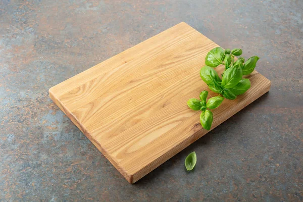 Mutfak masasında tahta ve fesleğen kesiyorum. Mutfak geçmişi. Boş tahta kesme tahtası, ürün görüntüleme alanı.