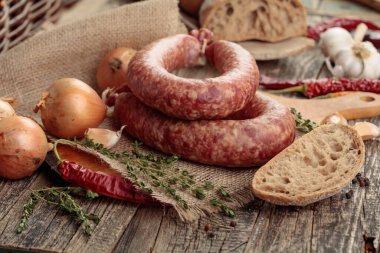 Kurutulmuş sosis, kekik, soğan, sarımsak ve biber. Eski ahşap bir masada sosis ve baharat..