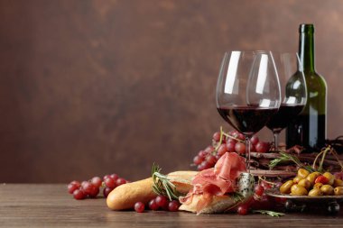 Prosciutto, mavi peynir ve kahverengi arka planda biberiyeli sandviç. Lezzetli aperatif ve kırmızı şarap. Boşluğu kopyala.