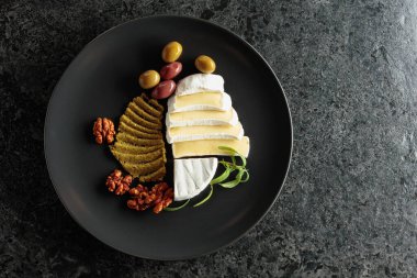 Siyah tabakta krem peynirli, zeytinli, biberiyeli ve cevizli. Üst görünüm.