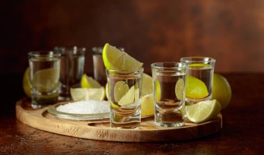 Tahta tepside tuz ve limon dilimleri ile altın tekila..