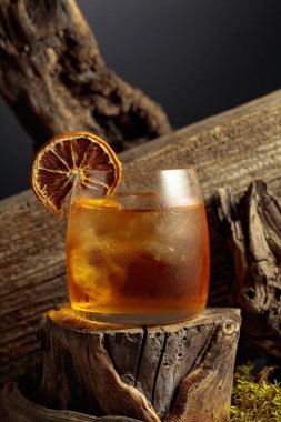 Eski moda bir karışım, buz ve kurutulmuş portakal dilimi ile eski ahşap bir kütükte.. 