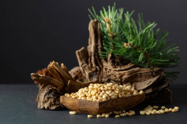 Çam fıstığı soyulmuş, sedir ağacı kurumuş ve yeşil dalları var. Siyah arka planda ahşap tabakta çam fıstığı.