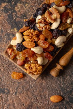 Sunulan kuru üzüm, ceviz, fındık, fındık, ceviz, ceviz ve badem. Kahverengi bir arka planda fındık ve kuru üzüm karışımı. Üst görünüm.