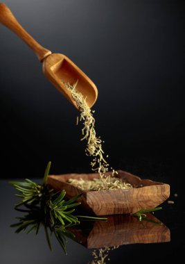 Siyah yansıtıcı arka planda biberiye. Kuru biberiye ahşap bir kaseye dökülür..