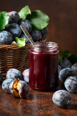 Kahverengi bir masada erik reçeli ve taze böğürtlen. Mutfak masasında reçelli olgun erikler..