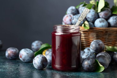 Lacivert arka planda erik reçeli ve taze böğürtlen. Mutfak masasında reçelli olgun erikler..