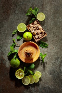 Tahta narenciye sıkacağı ve yaz ferahlatıcı içecekler yapmak için malzemeler. Esmer şeker, limon ve taş bir masada taze nane dalları. Üst görünüm.