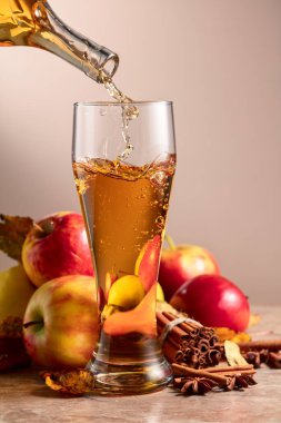 Elma suyu bardağa dökülür. Elmalı, tarçınlı ve bej arkaplanlı taze içecek..