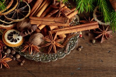 Gümüş tepside kurutulmuş narenciye dilimli çeşitli Noel baharatları. Noel ağacının baharatları ve dalları eski ahşap bir masada..