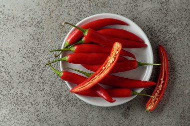 Gri taş bir masada yeşil saplı taze kırmızı biber. Üst görünüm, alanı kopyala.