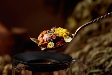 Eski kaşıkta çeşitli kurutulmuş otlar ve baharatlar. Aromaterapi ya da bitkisel ilaç konsepti. Boşluğu kopyala.