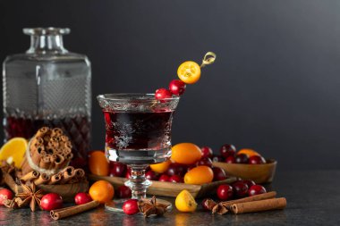 Siyah arka planda baharatlar, kızılcıklar ve narenciye meyveli bir içecek. Boşluğu kopyala.
