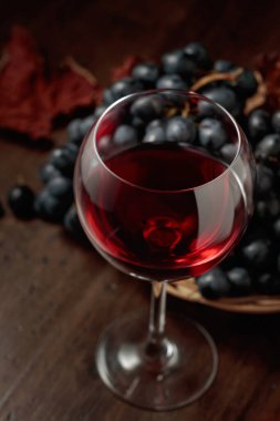 Eski ahşap bir masada kırmızı şarap ve mavi üzüm. Seçici odak.