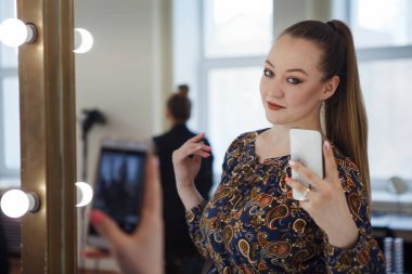 Sevimli kadın kendini selfie smartphone cep telefonu ile yapıyor ayna görünümlü makyaj yapma