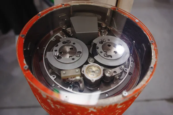 The exhibit of the scientific cognitive museum is a complex mechanism of gears and rings under glass