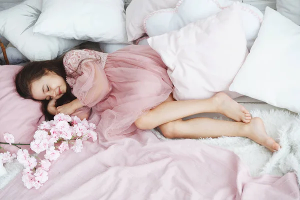 Μικρό Κορίτσι Ένα Ροζ Φόρεμα Που Βρίσκεται Ένα Κρεβάτι Λευκά — Φωτογραφία Αρχείου