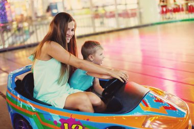 Aile Anne ve küçük çocuk bir eğlence parkı oyun makinesi araba arcade sürüş.