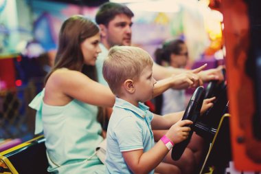 Aile Anne, baba ve küçük çocuk bir eğlence parkı oyun makinesi araba arcade sürüş.