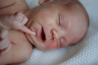 Yedi günlük eski bebek arkasında uyuyor. Çocuk bir battaniyeye sarılmış ve duygular uyku sırasında ifade eder. Yakın çekim.