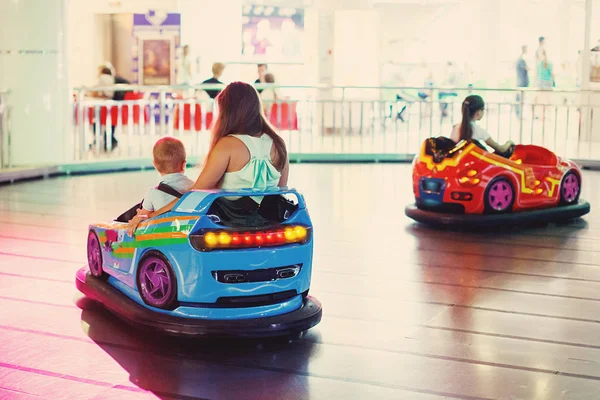 ホストファミリーのお母さんが 十代の女の子と遊園地でゲーム機で運転して車アーケード少年 — ストック写真