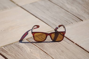 Güneş gözlüğü gri bir ahşap arka plan üzerinde yalan. Önden görünüm, kahverengi cam.